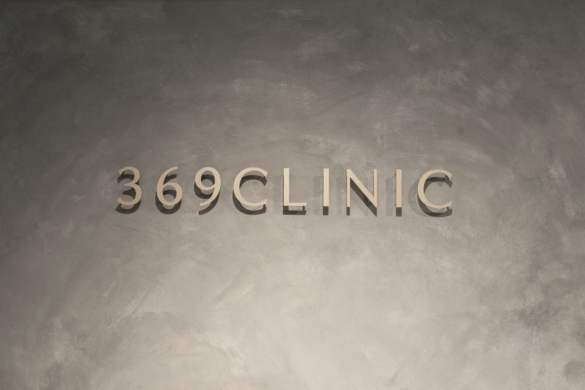 モルタル壁に映える 369CLINIC のゴールドロゴ